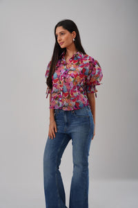 Woman wearing a colorful floral blouse and blue jeans on a gray background